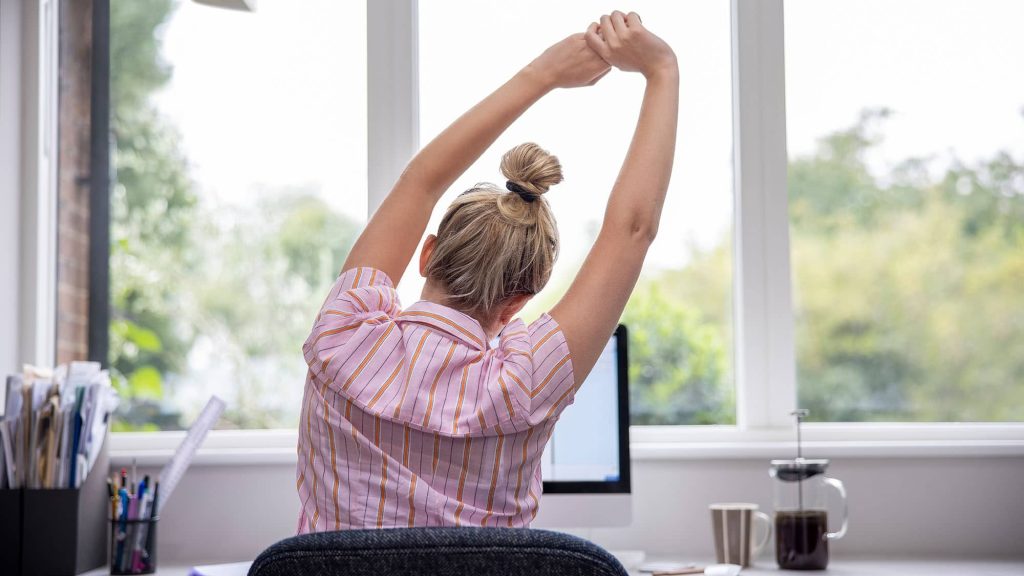 femme de dos s'étire devant PC