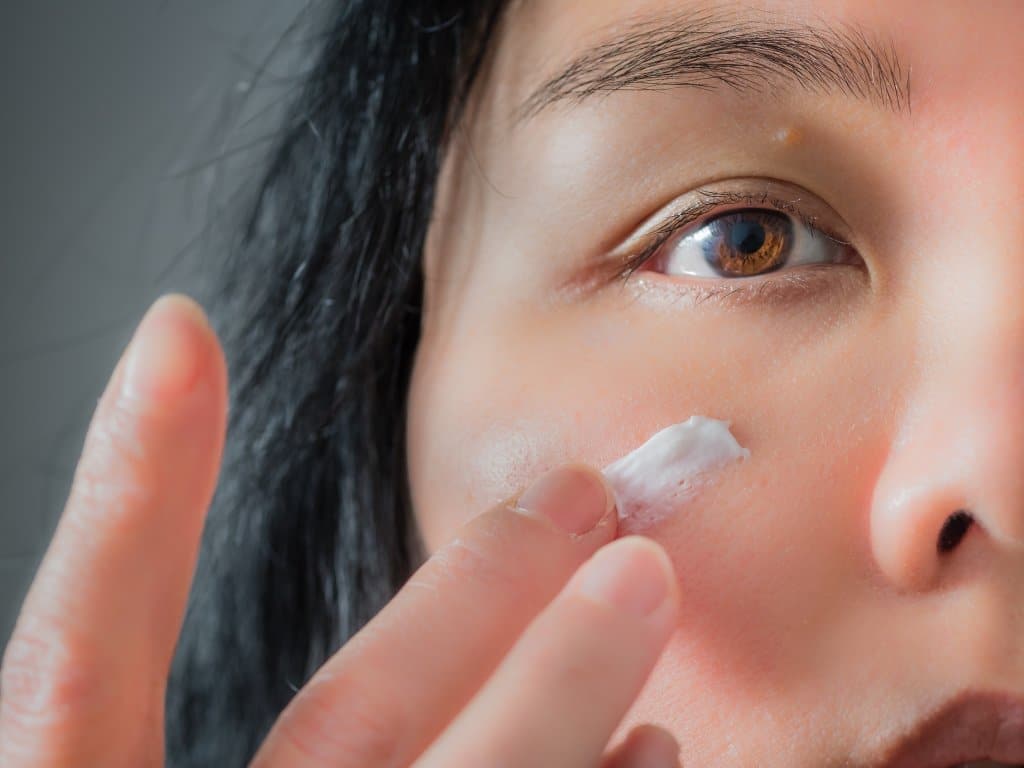 femme s'appliquant de la crème sur le visage