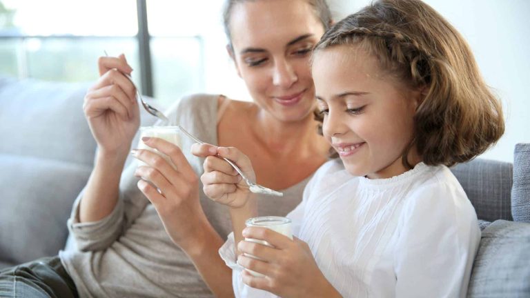 une mère et sa fille mangent un yaourt