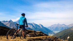 Une aventure de 8000kms à vélo pour la protection des forêts Une personne de dos est à vélo face à la montagne.