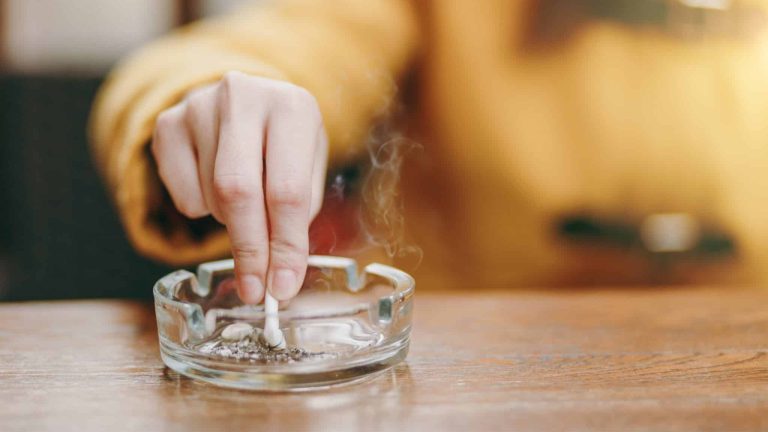 Une femme écrase une cigarette dans un cendrier.