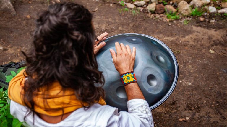 femme de dos qui joue du hand pan dans la nature