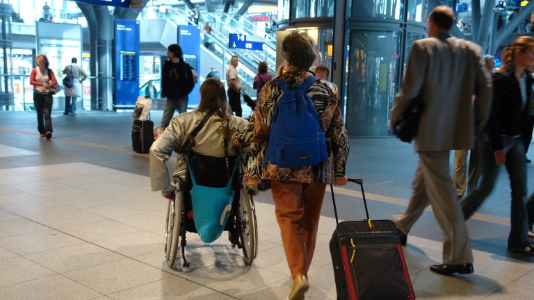 Une personne en fauteuil dans une gare.