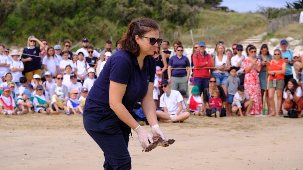 Florence Dell'Amico s'apprête à relâcher dans l'océan une tortue marine. Elle est entourée de 500 personnes