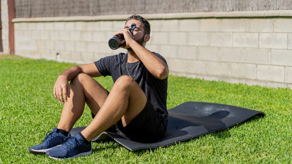 Un homme sur un tapis d'exercice boit.