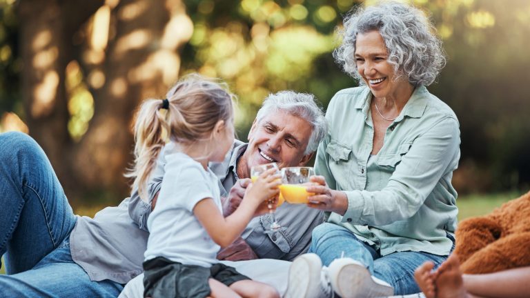 Une famille pique-nique et boit un jus d'orange.