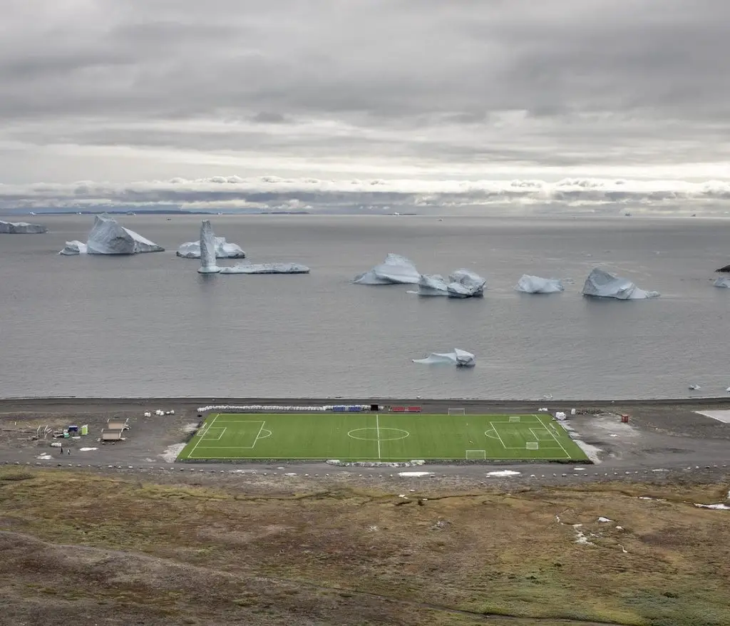 Le stade de foot en herbe synthétique de Qe-qertarsuaq, au Groenland. Il accueille le plus court championnat de football au monde qui, à cause des très basses températures, se jour une seule semaine.