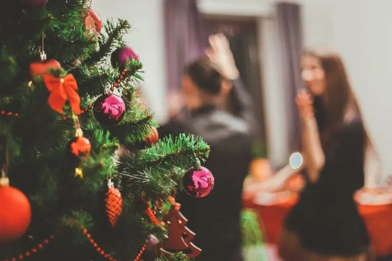 Un sapin de Noël décoré et en arrière-plan des gens s'amusent