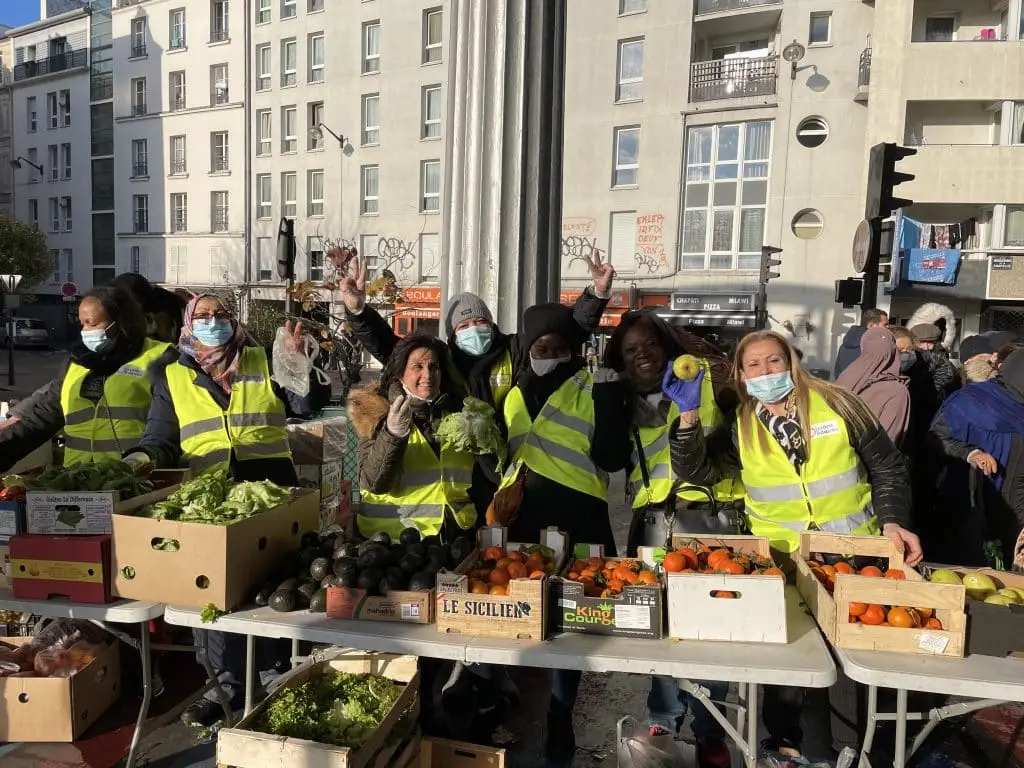 Des bénévoles présentent à une distribution solidaire de fruits et de légumes.