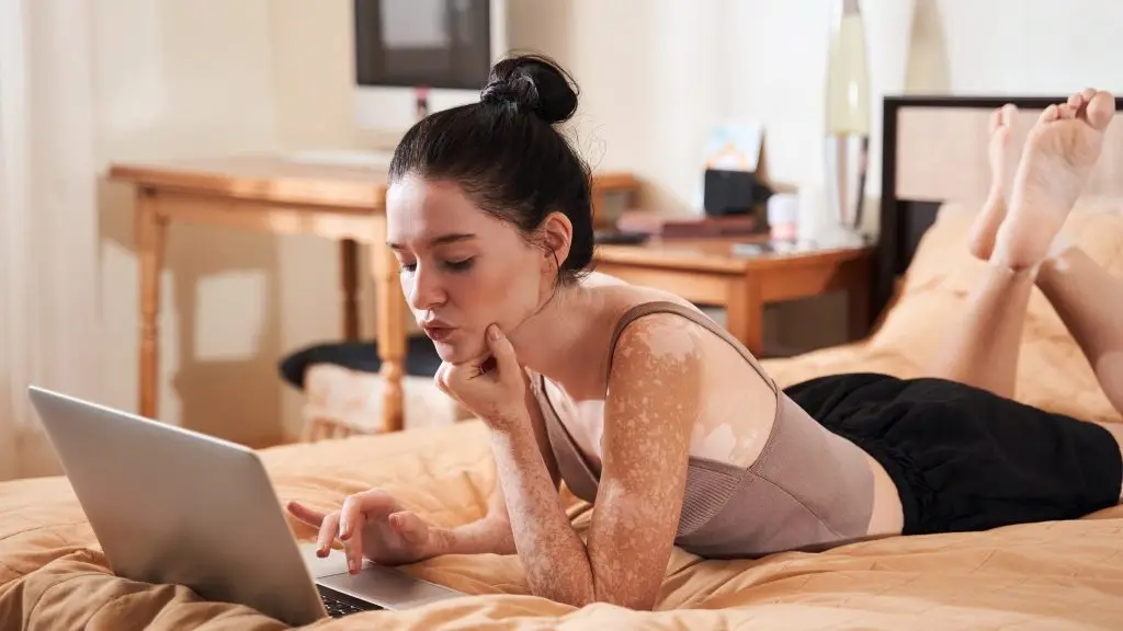 Une femme allongée sur son lit avec un ordinateur.