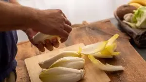 Un homme cuisine des endives.