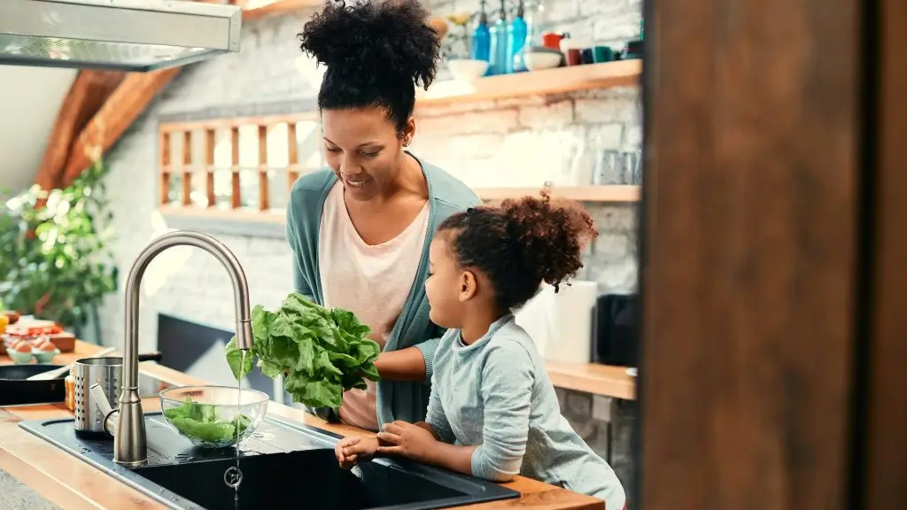 Une femme et sa fille dans une cuisine lavent une laitue.