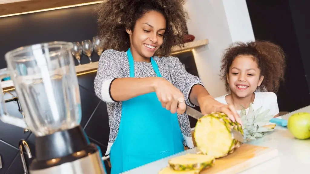 Une mère et sa fille en cuisine coupent un ananas.