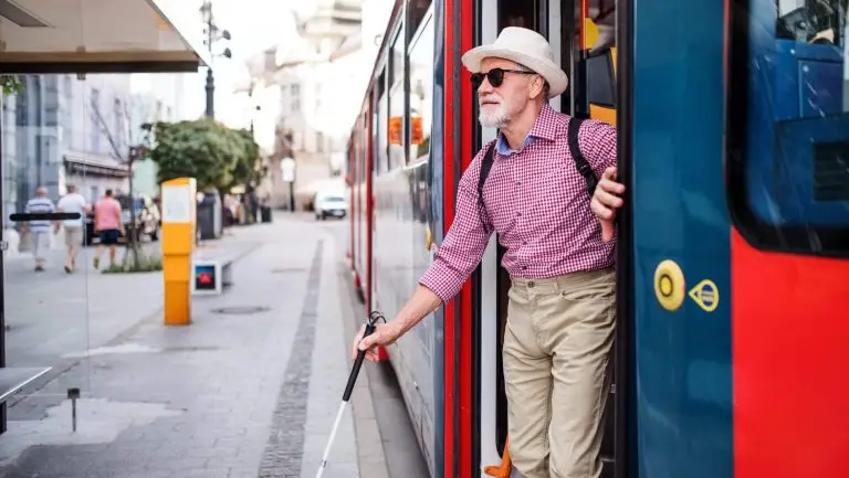 Une personne en situation de handicap visuel descend d'un tram