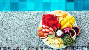 une assiette de fruits pour l'hydration, posée sur le rebord d'une piscine