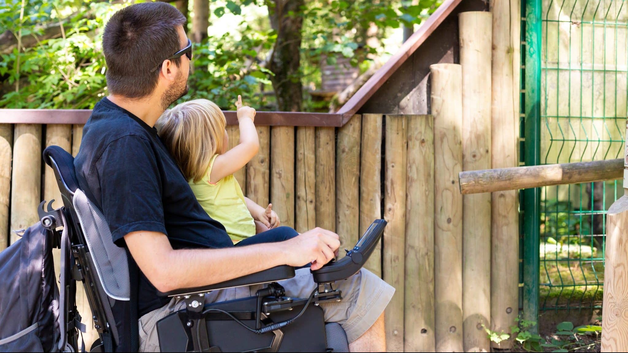 Un père en situation de handicap avec sa fille sur les genoux.