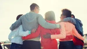 Un groupe de 4 personnes s'entrelacent. Elles sont de dos