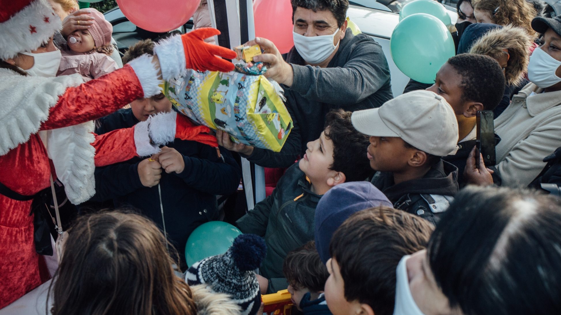 Une personne déguisée en Père Noël distribue des jouets.