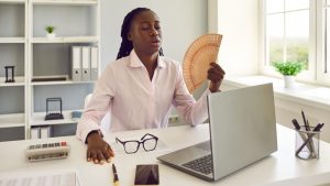 Une femme dans un bureau s'évente à cause de la chaleur