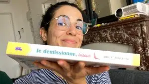 Sonia Benyahia tient son livre "Je démissionne, bisous". Elle porte de lunettes de vue et elle sourit.