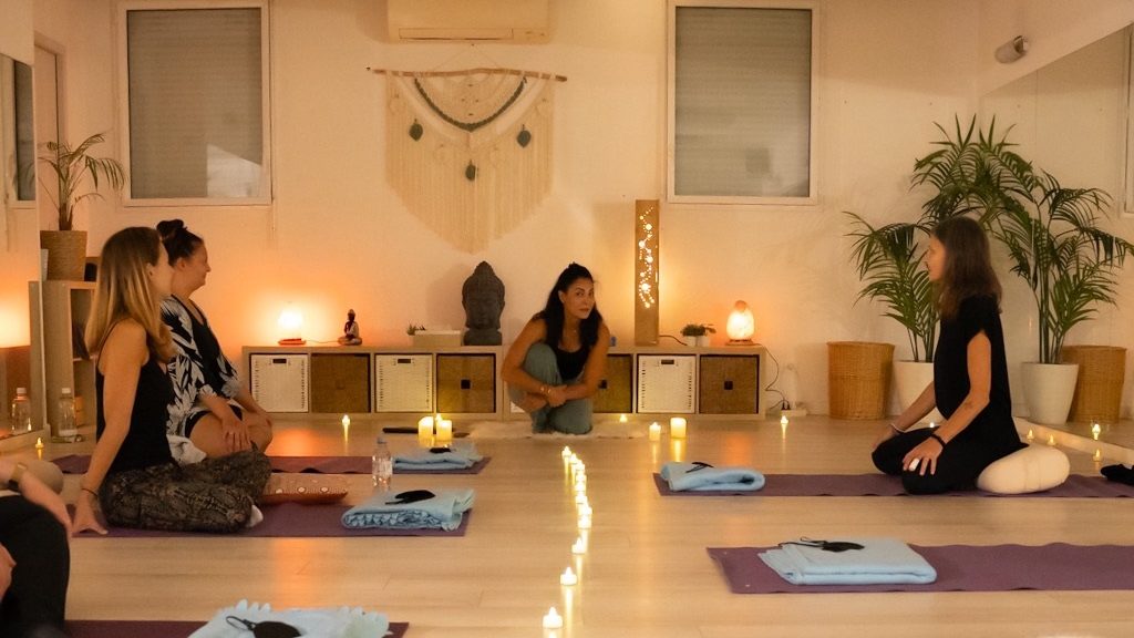 Une séance de breathwork avec la sophrologue Loubna Lamri. Des femmes sont assises par terre sur un tapis dans une salle. Il y a quelques bougies.