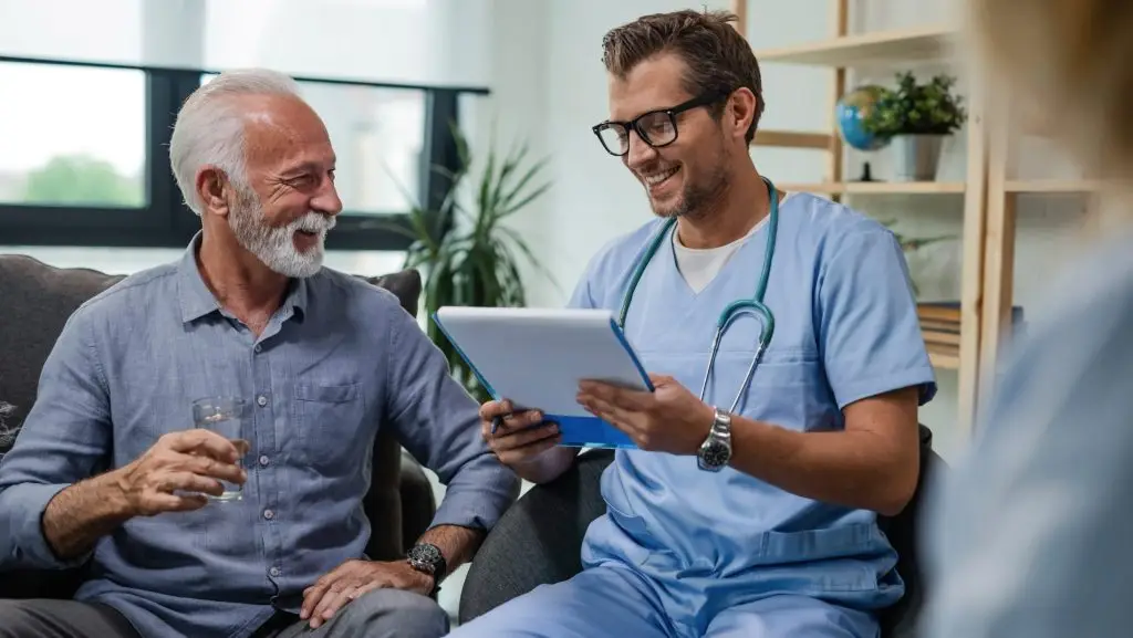 Un homme âgé et un homme médecin sont assis l'un à côté de l'autre. Ils sourient