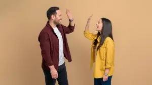 Un homme et et une femme sourient. Ils se font face et s'apprêtent à se taper dans la main.