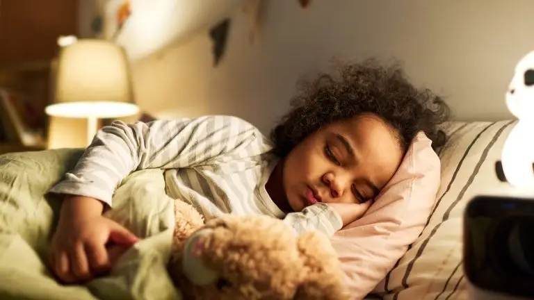 Un enfant est endormi dans son lit avec son doudou