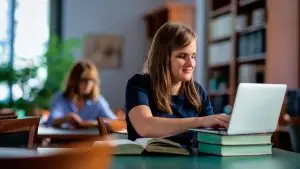 Une femme avec une déficeince visuelle est assise à un bureau. Elle utilise son ordinateur