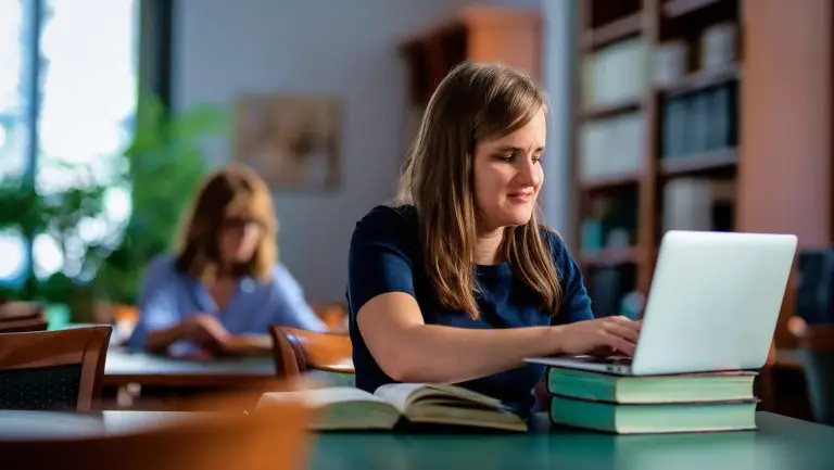 Une femme avec une déficeince visuelle est assise à un bureau. Elle utilise son ordinateur