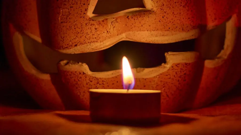 A carved pumpkin and a candle in a dark background - halloween concept