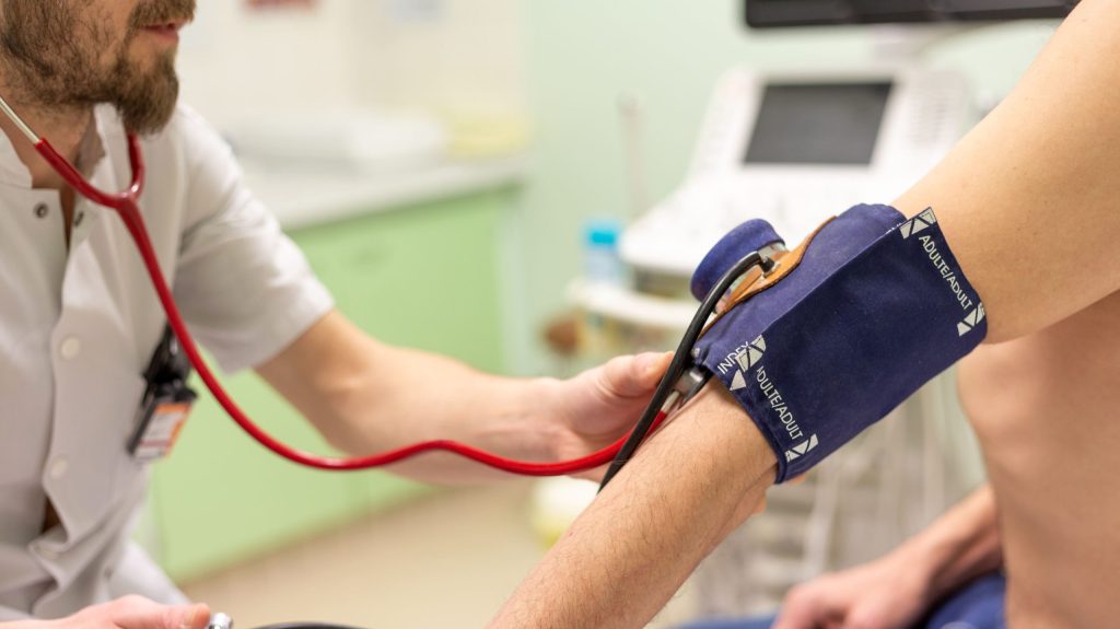 Un médecin prend la tension de son patient.