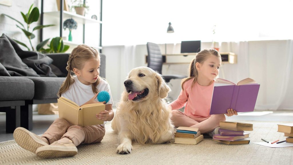 Deux petites filles lisent en présence d'un chien