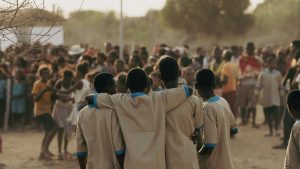 Quatre enfants à madagascar, heureux, de dos devant une foule