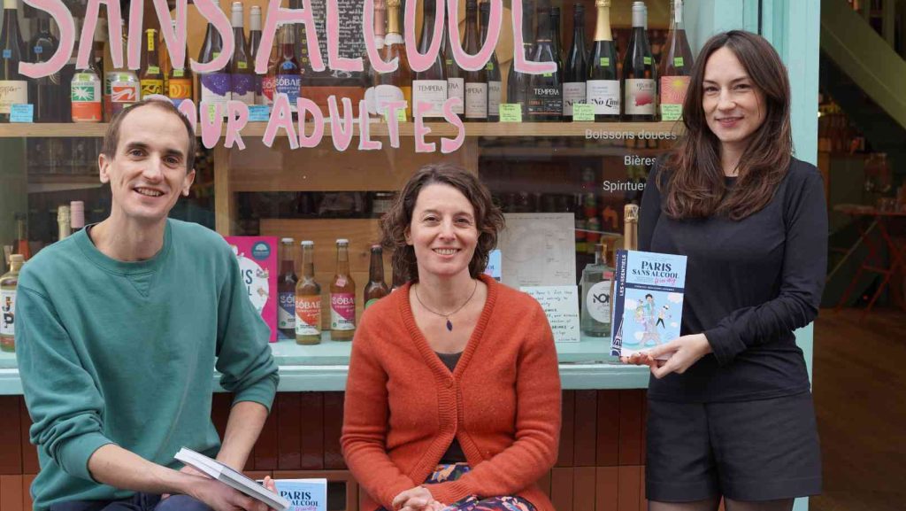 Augustin Laborde, Raphaële Bortolin et Maud Catté sont devant la devanture du Paon Qui Boit, cave sans alcool à Paris. En souriant, ils présentent leur livre " Paris sans alcool friendly ".