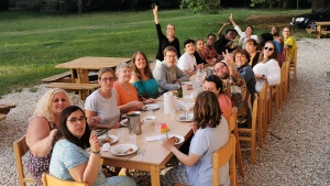 photo d'un repas en extérieur, devant une bâtisse l'ambiance est joyeuse