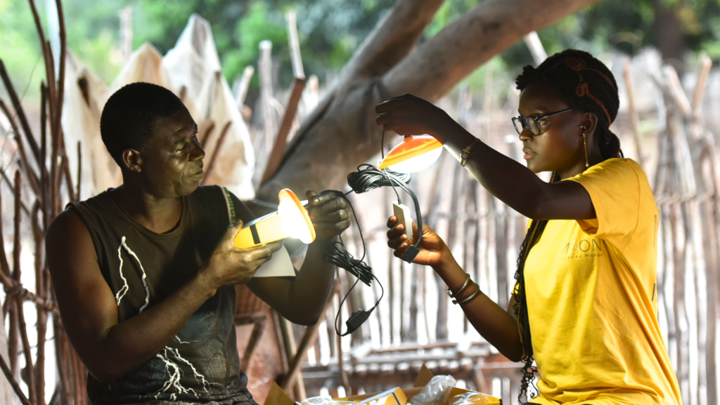 Un homme et une femme sont en train de manipuler un kit solaire et des lampes qui sont allumées en plein jour.